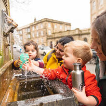 Two women and two small children getting water from a fountain