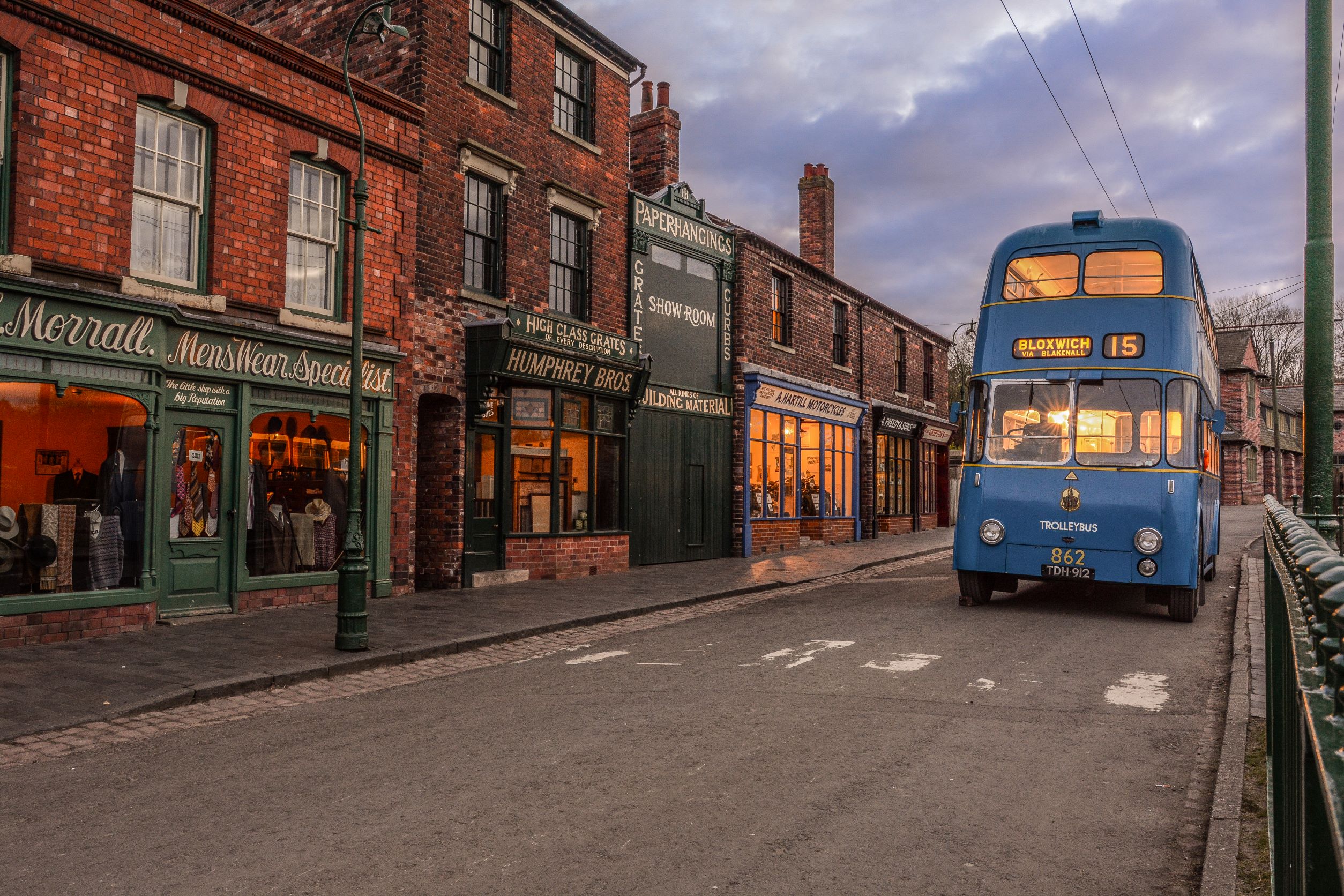 Un autobus blu vintage che percorre una strada in un museo vivente