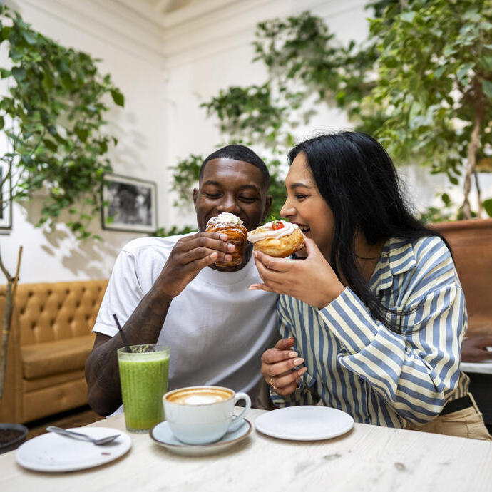 A man and a woman have cake and drinks in a cafe