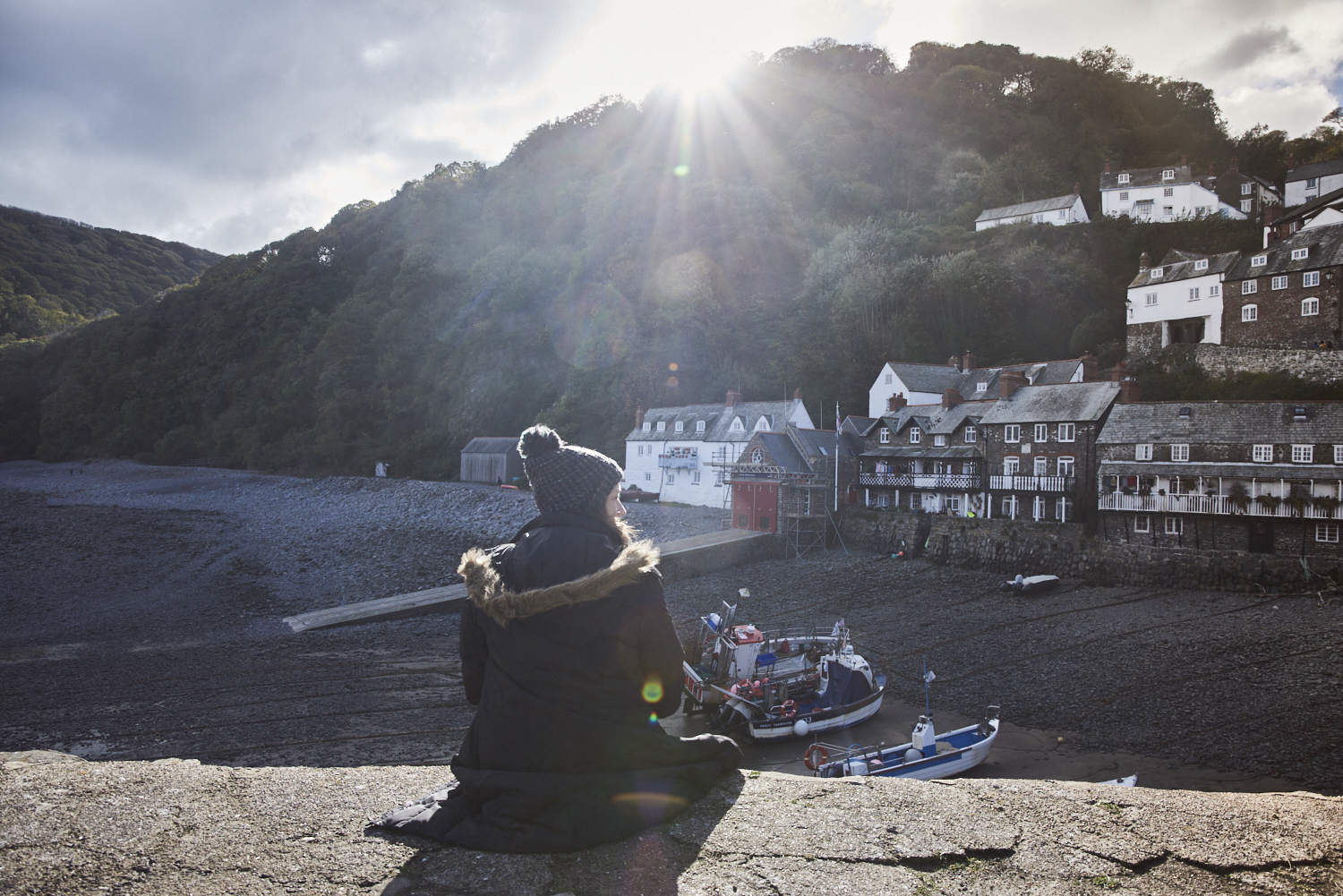Femme assise sur le mur du port, au soleil