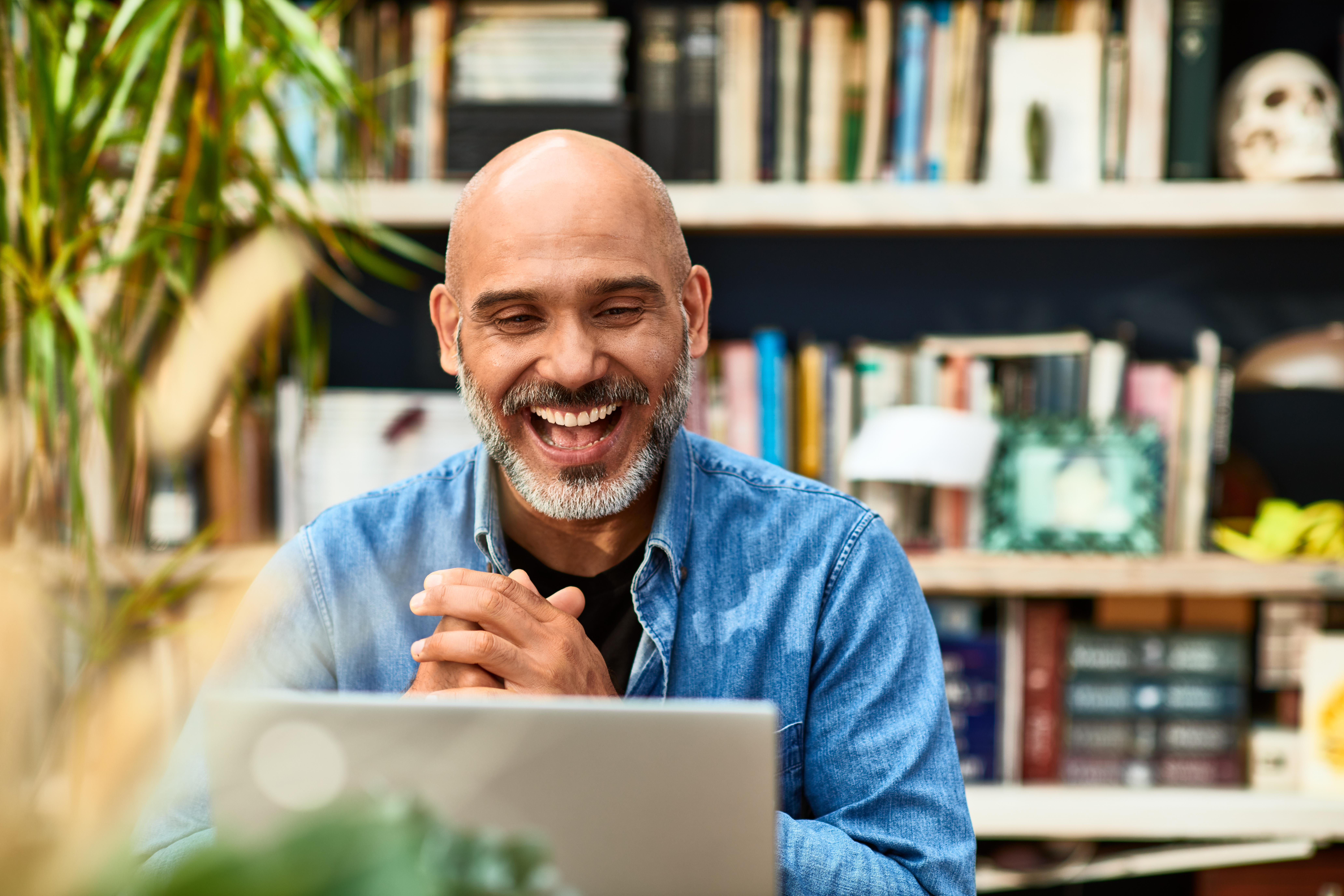 Cheerful handsome mature man at home speaking on video call using laptop