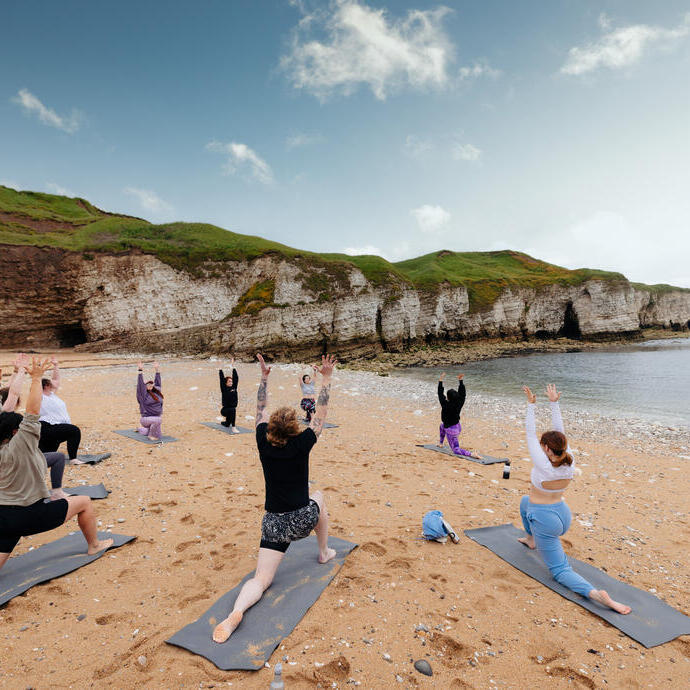 Eine Gruppe von Menschen praktiziert Yoga am Strand