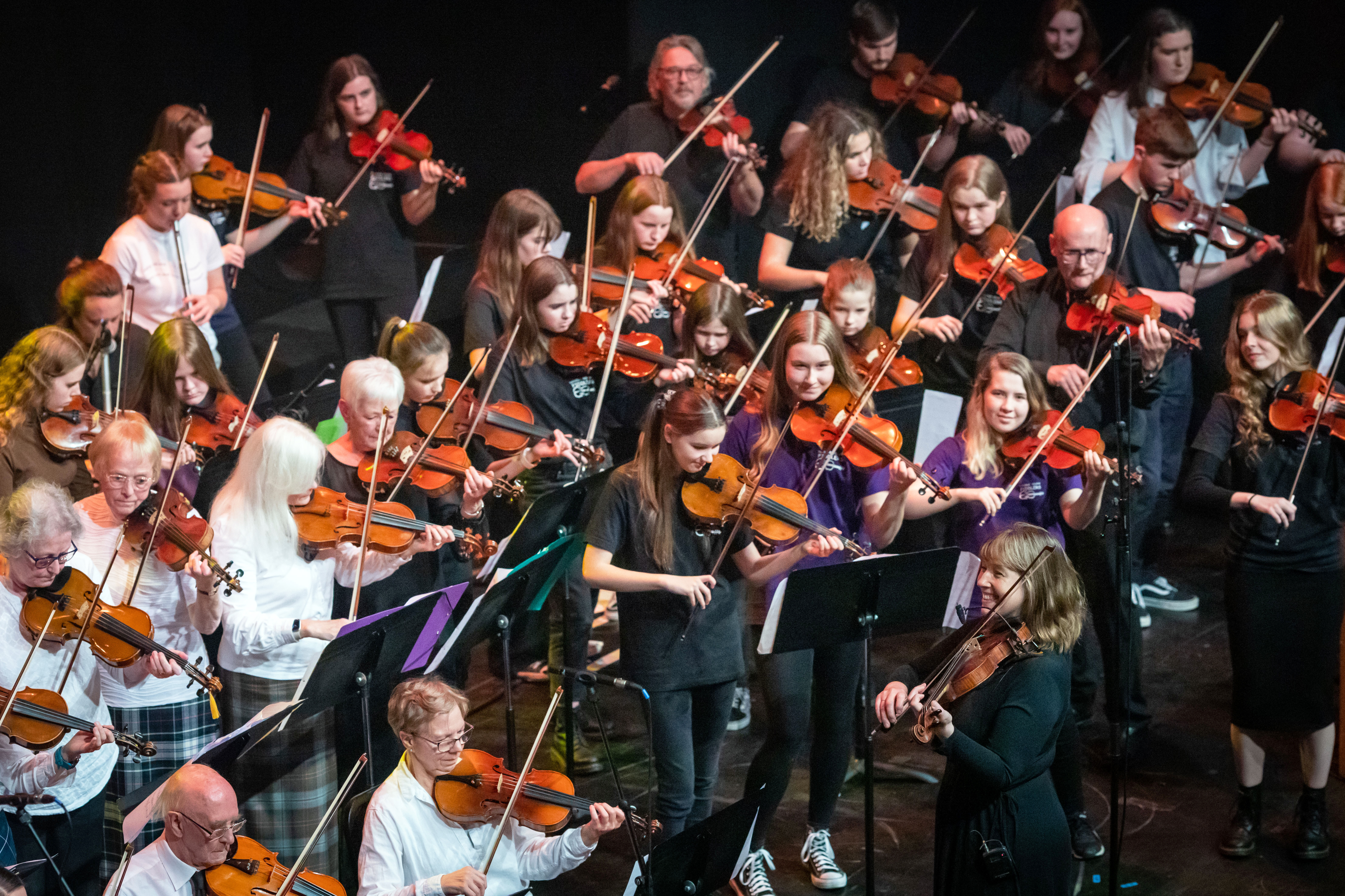 Patsy Reid performs on stage with fiddlers at the Our Language, Our Music concert at Perth Concert Hall