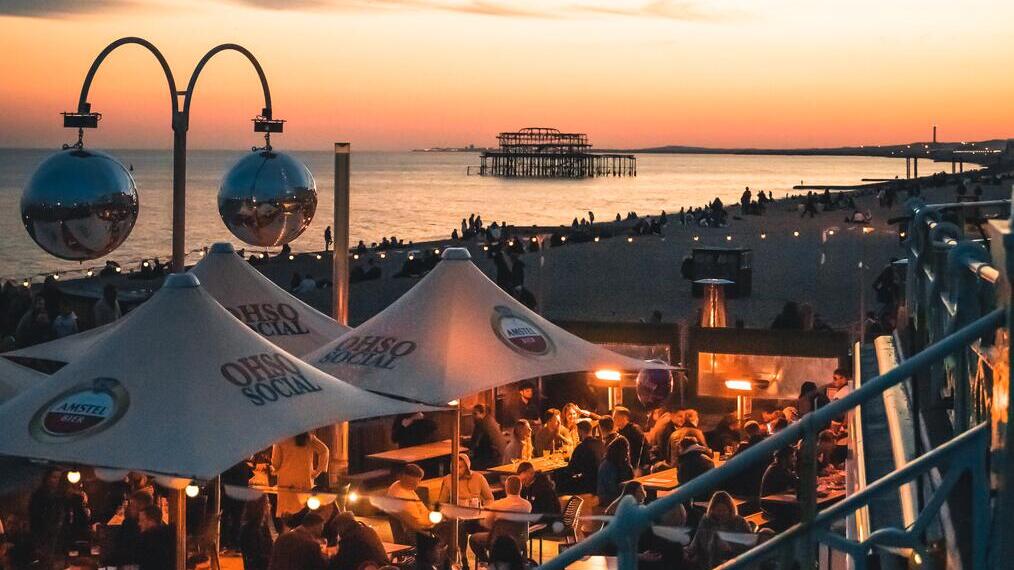 Des personnes prennent un verre dans un bar en bord de mer au coucher du soleil