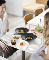A man and a woman sit at a table with food and drinks inside a restaurant