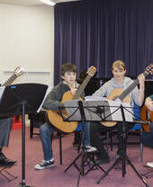 A group of people preparing to play guitars on stage as part of Oxford Music Festival