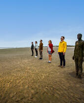 People standing in line beside a statue on the beach
