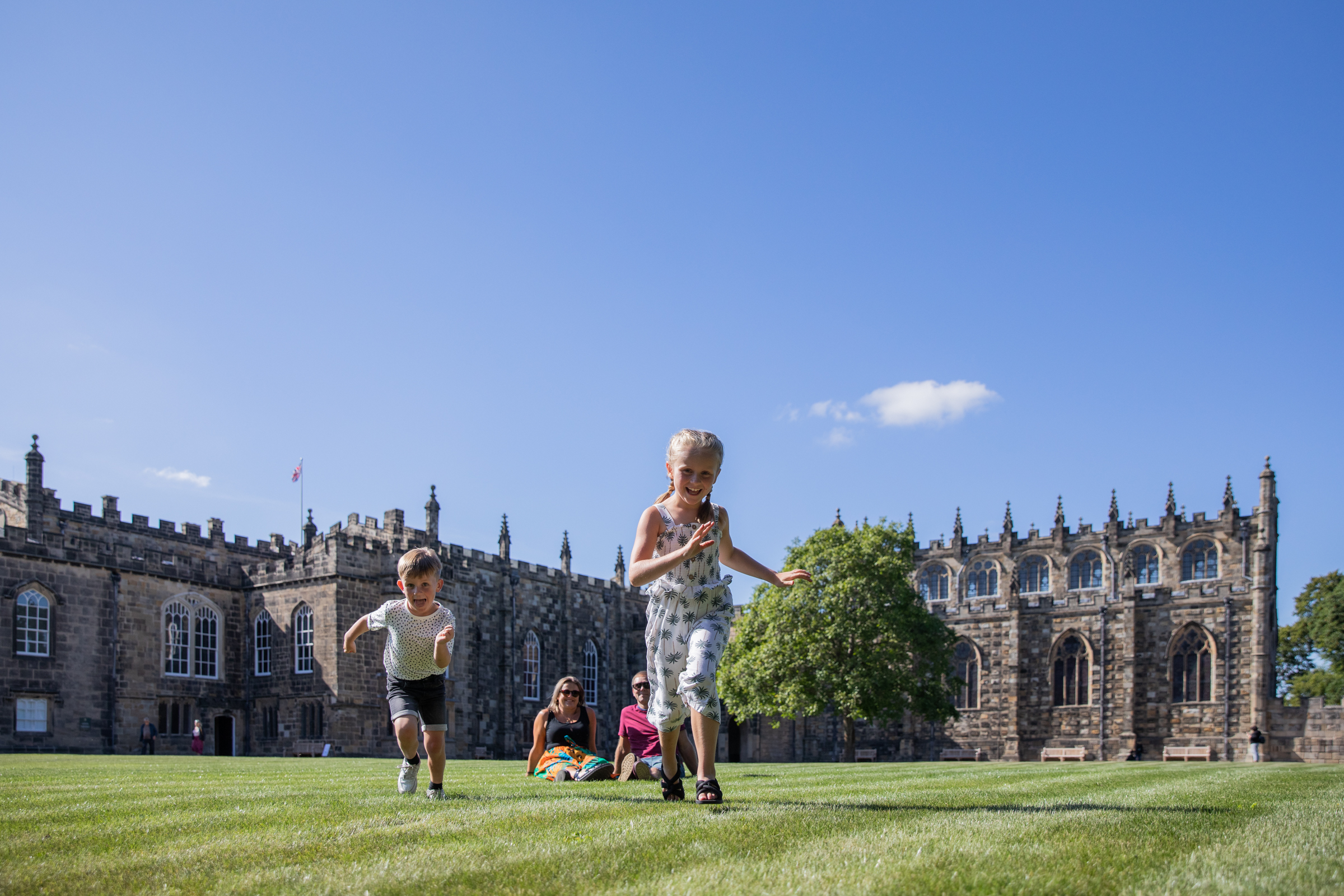 Una famiglia che corre su un prato davanti a un edificio storico a Durham