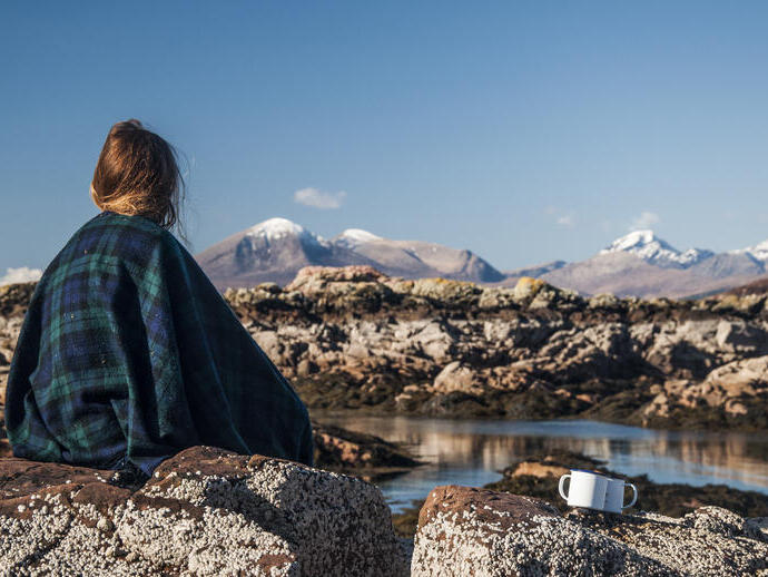 Mujer sentada en una roca mirando las montañas en la distancia