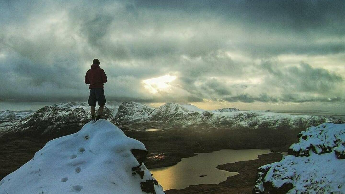 Personne au sommet d'une montagne enneigée contemplant le paysage
