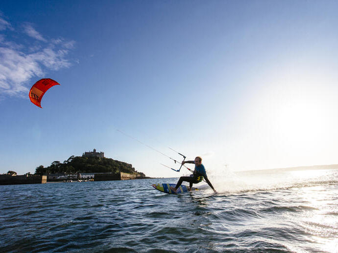 Un uomo su una tavola da surf che tiene la barra di controllo di un aquilone
