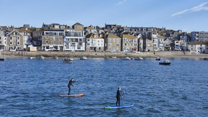 Two people on paddle boards floating in a harbour