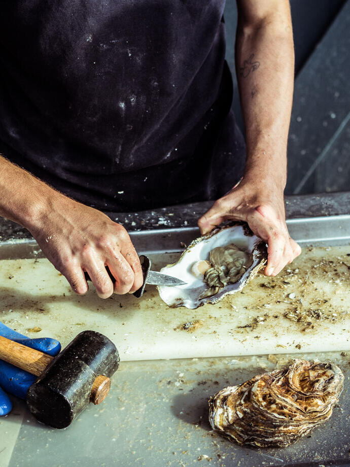 A man prepares an oyster at a seafood market in Whitstable, England