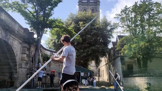 A man enjoying a punt down the river, next to Oxford University