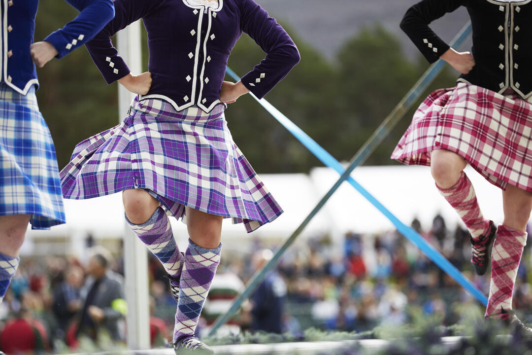 Three kilted girls Scottish dancing on stage