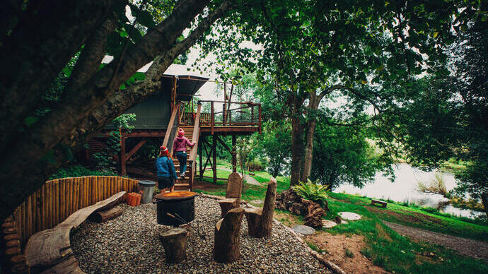 Amigos haciendo glamping a la orilla del agua en un bosque.