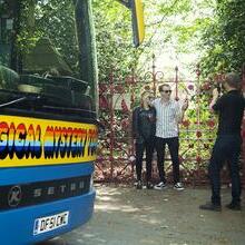 People pose for photo in front of gates on the Magical Mystery Tour in Liverpool