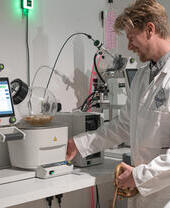 A man in a lab coat using a distillery machine