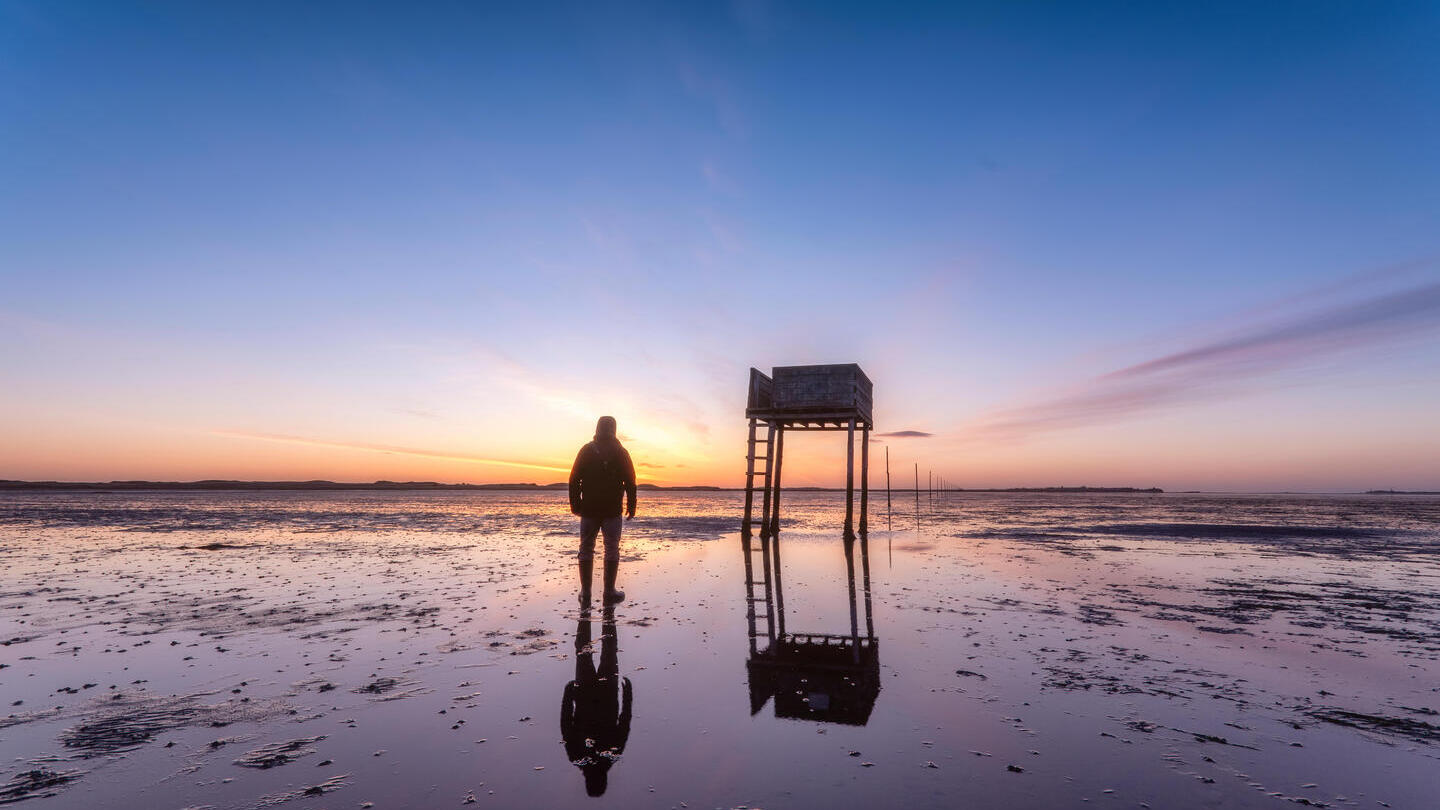 Pfosten markieren den Pilgerweg nach Lindisfarne mit Notunterkunft bei Sonnenaufgang