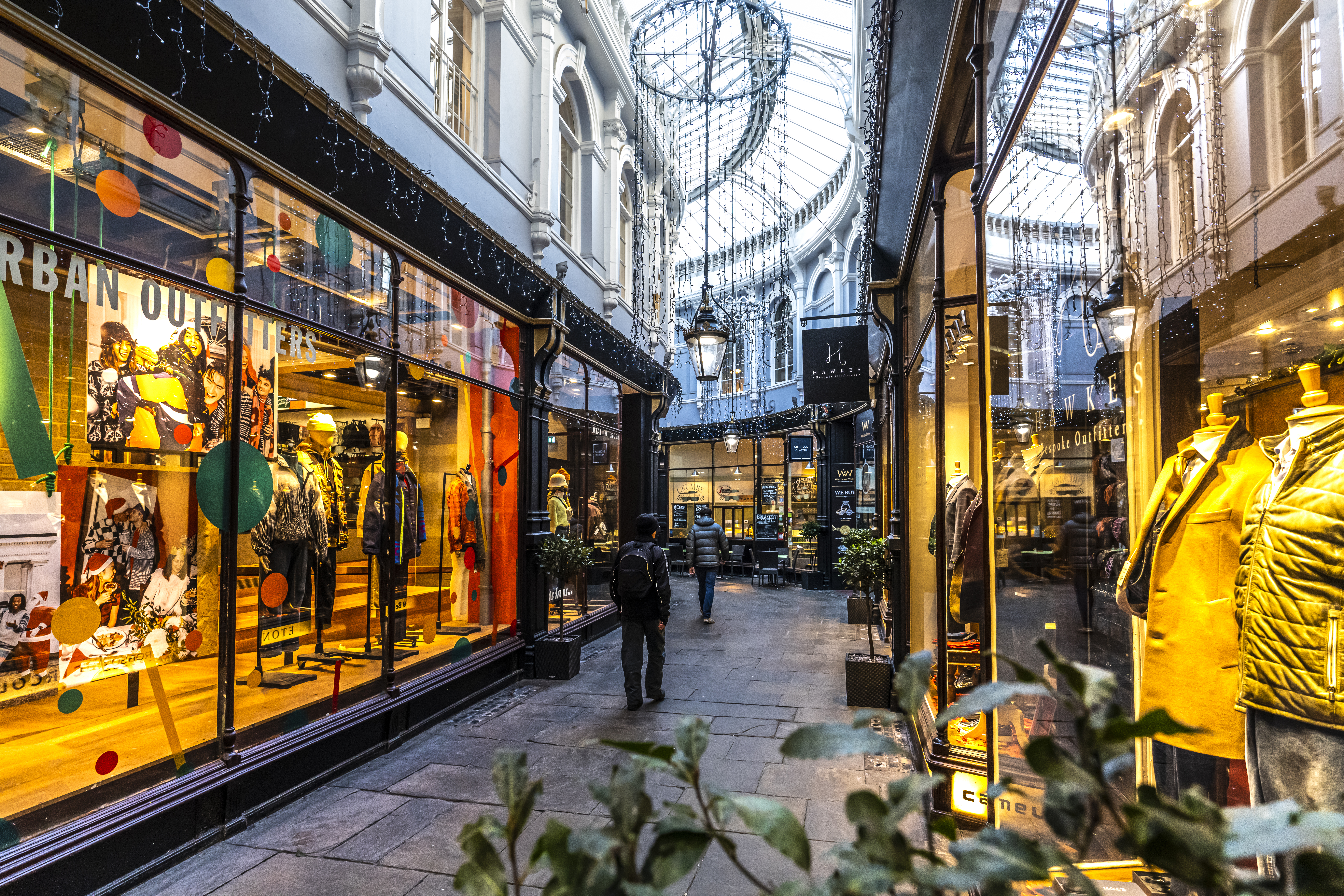 Des gens marchant entre les magasins d'une galerie marchande éclairée de l'intérieur
