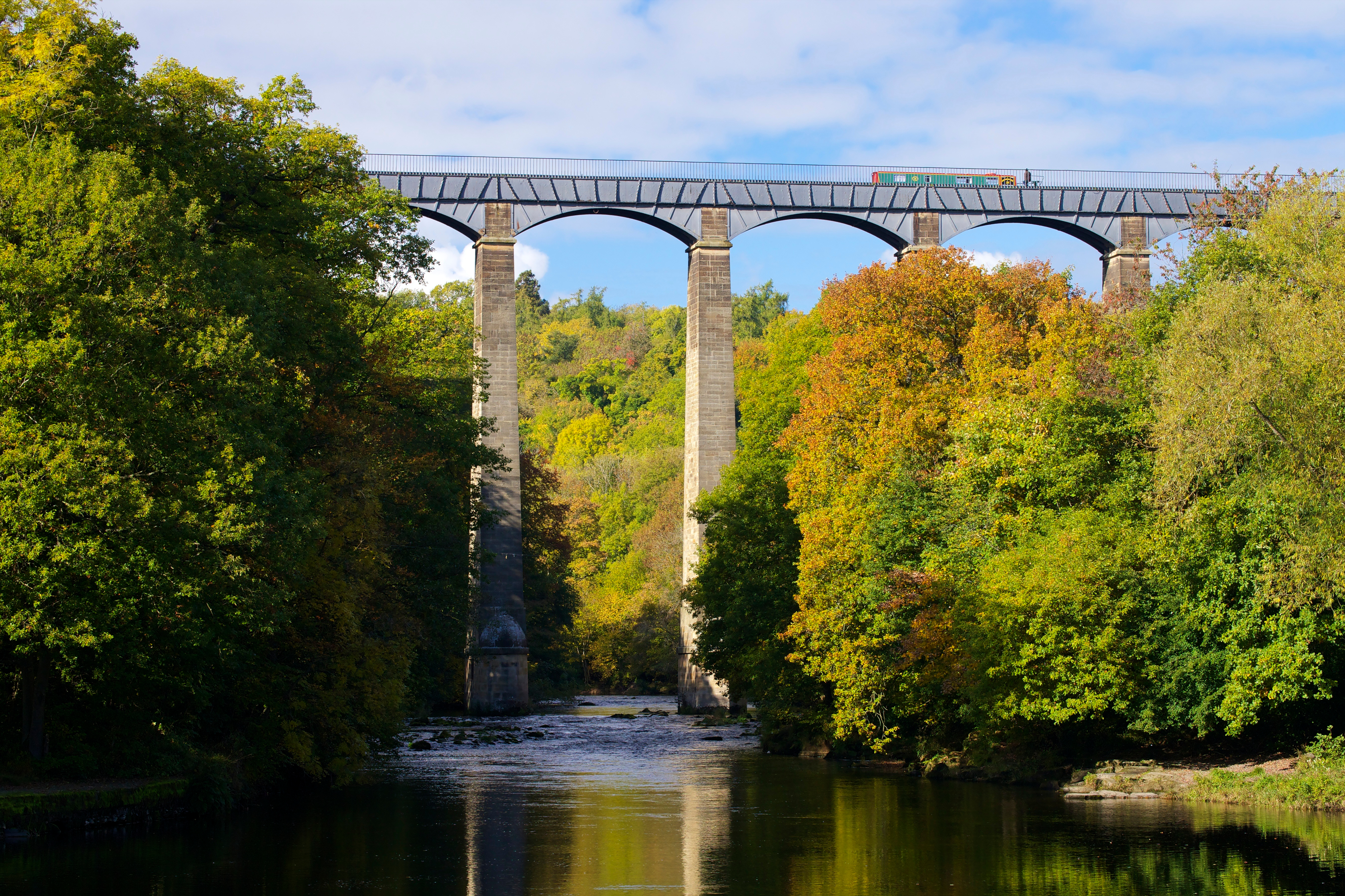 A tall aqueduct spanning a pretty stream.