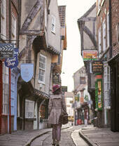 Frau, die durch eine enge historische Straße in einer Stadt geht