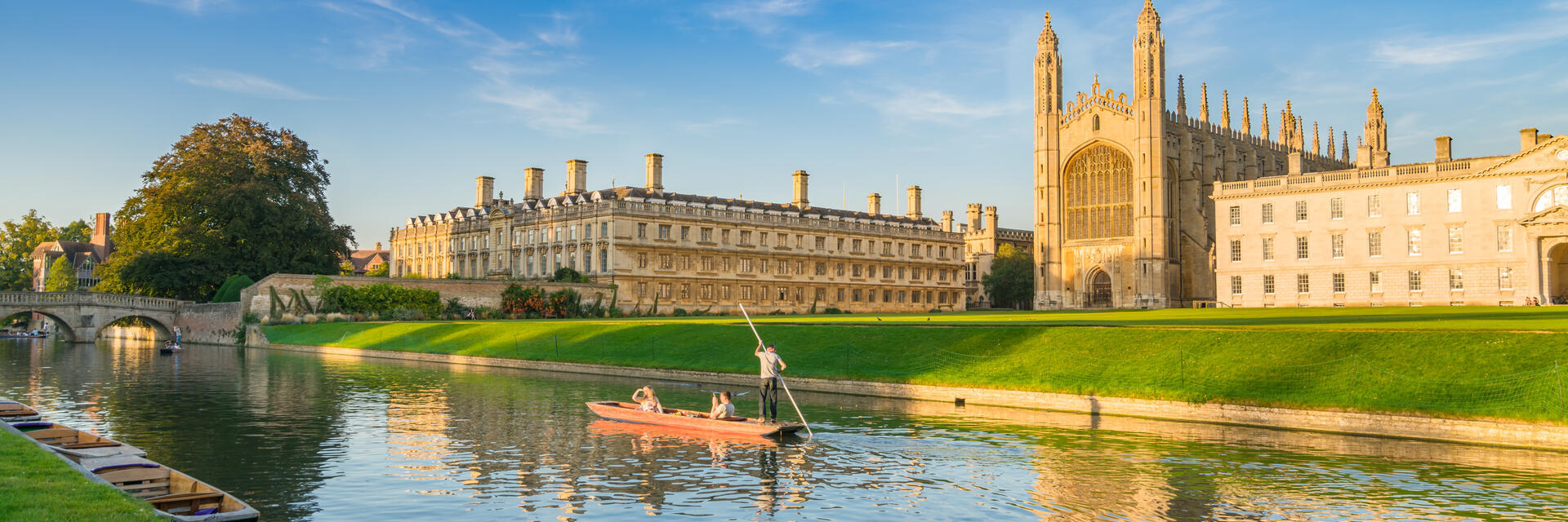 People punting along a river next to a college and chapel.