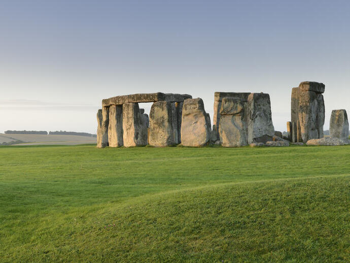 Large stone pillars arranged in circle on grass at sunset