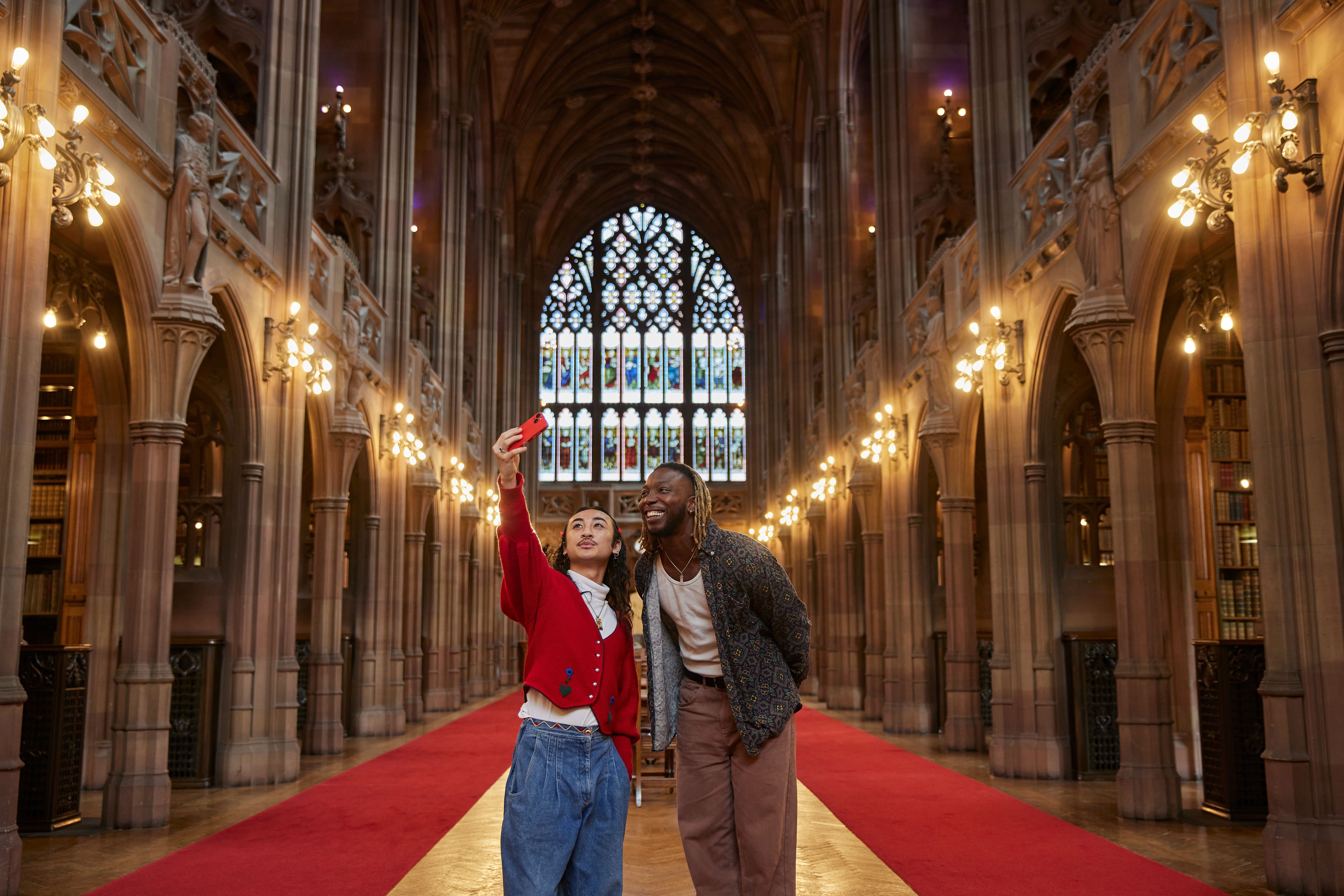 Zwei Männer machen ein Selfie in einer großen Bibliothek.