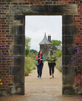 Two women walking toward archway, RHS Bridgewater