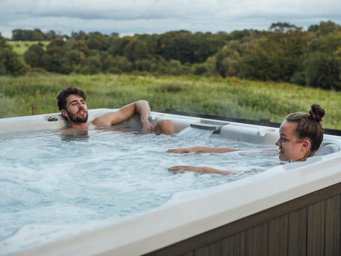 Couple relaxing in a hot tub overlooking countryside