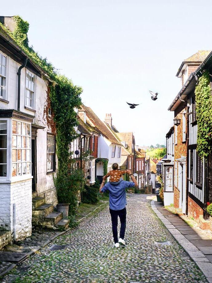 Man carrying child on his shoulders walking along street