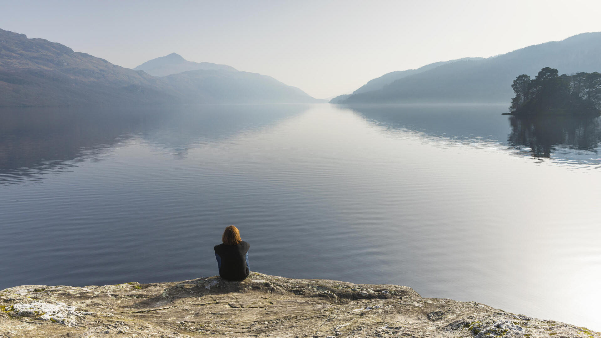 A woman sitting and looking out across Loch Lomond