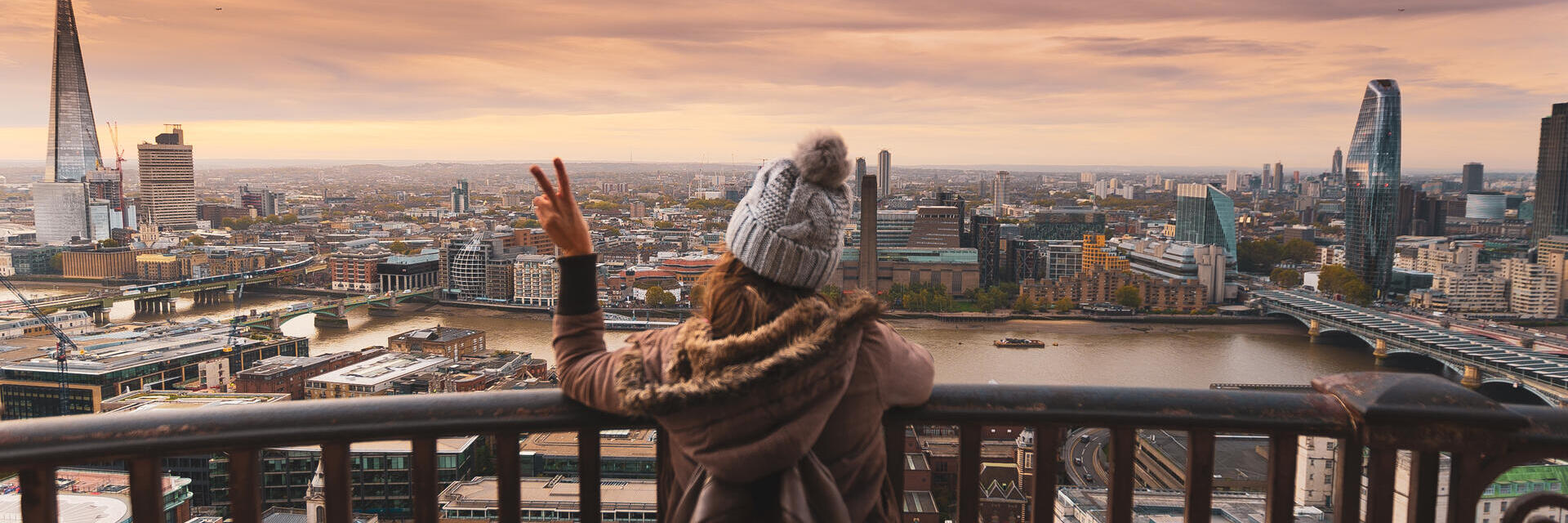 Une femme sur le balcon d'un immeuble haut, contemplant la ville
