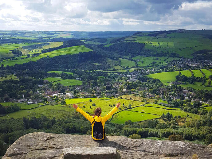 Una mujer con los brazos levantados disfrutando de la vista desde lo alto