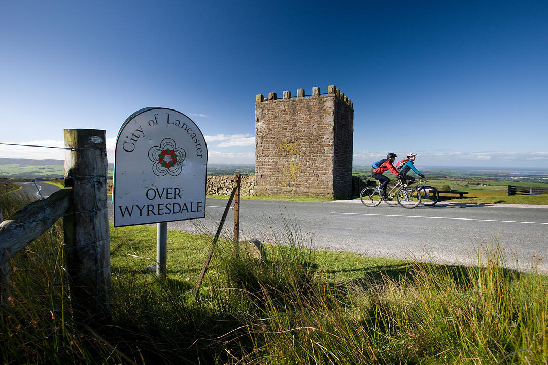 Two people cycling past Jubilee Tower near the city of Lancaster
