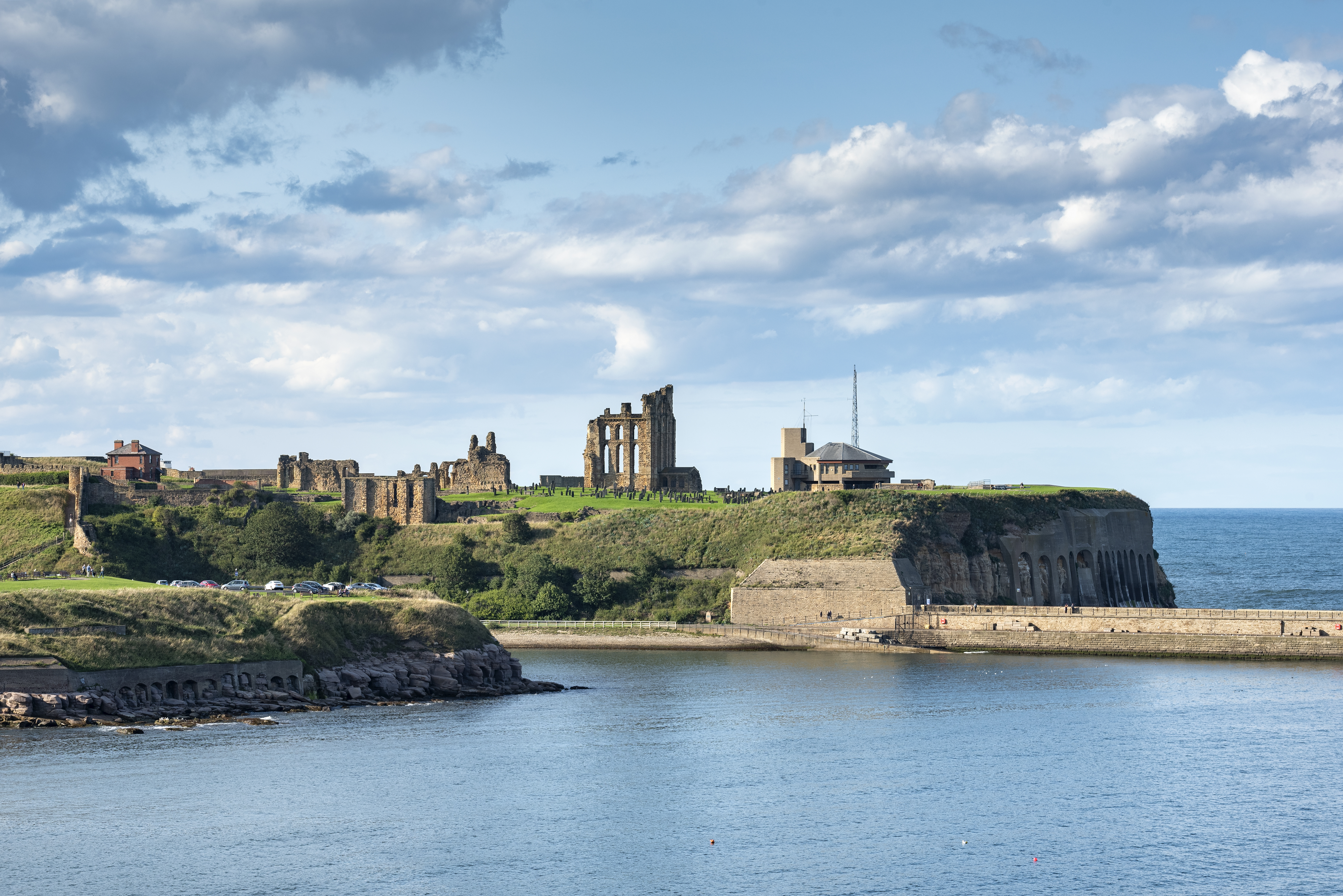View of priory and castle ruins and a coastguard station on the coast