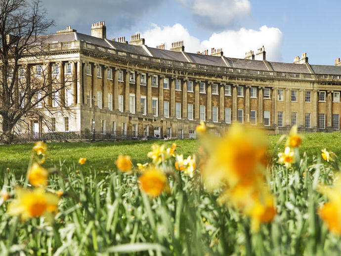 External view of regency style curved row of buildings with a field of blurred out daffodils in the foreground.