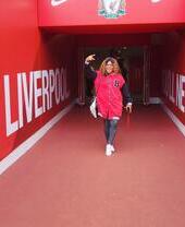 A woman posing while on a stadium tour of Anfield, Liverpool.
