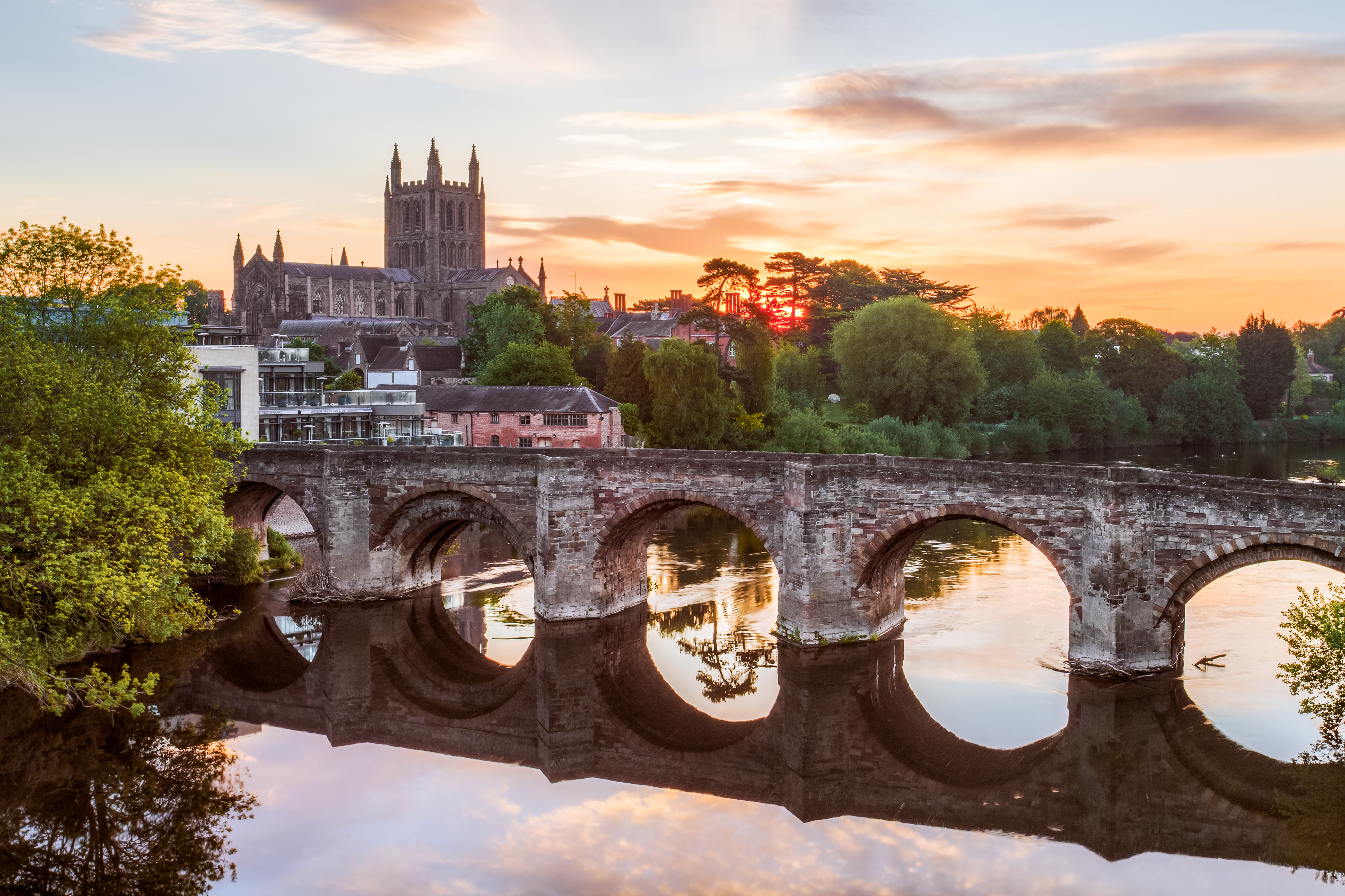 Roman Bridge over a river with a cathedral in background at sunrise