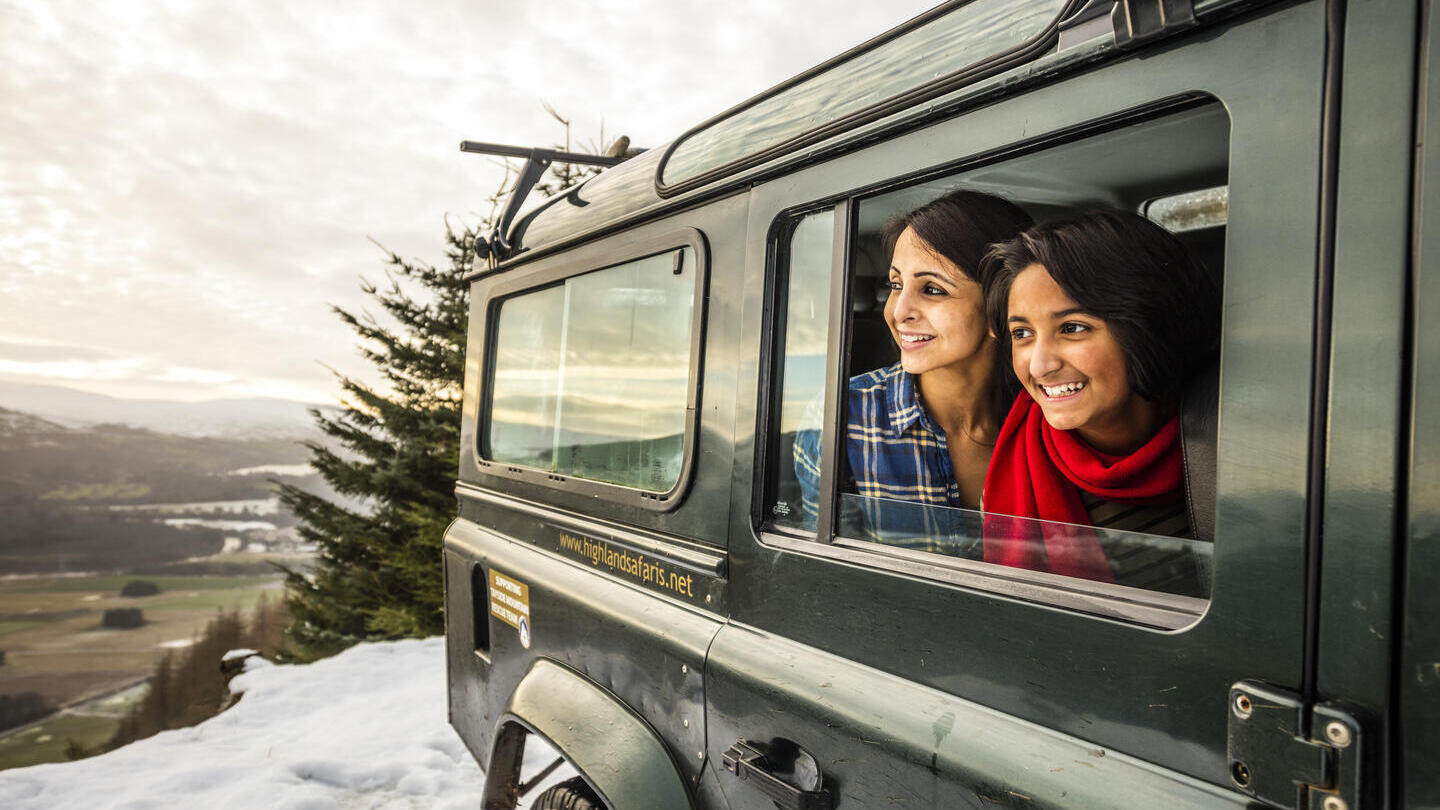 Mujer y adolescente mirando por la ventana de un jeep en la nieve