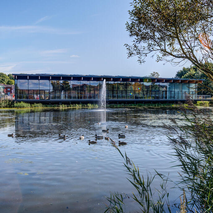 View of lake complete with fountain and ducks to a glass fronted building