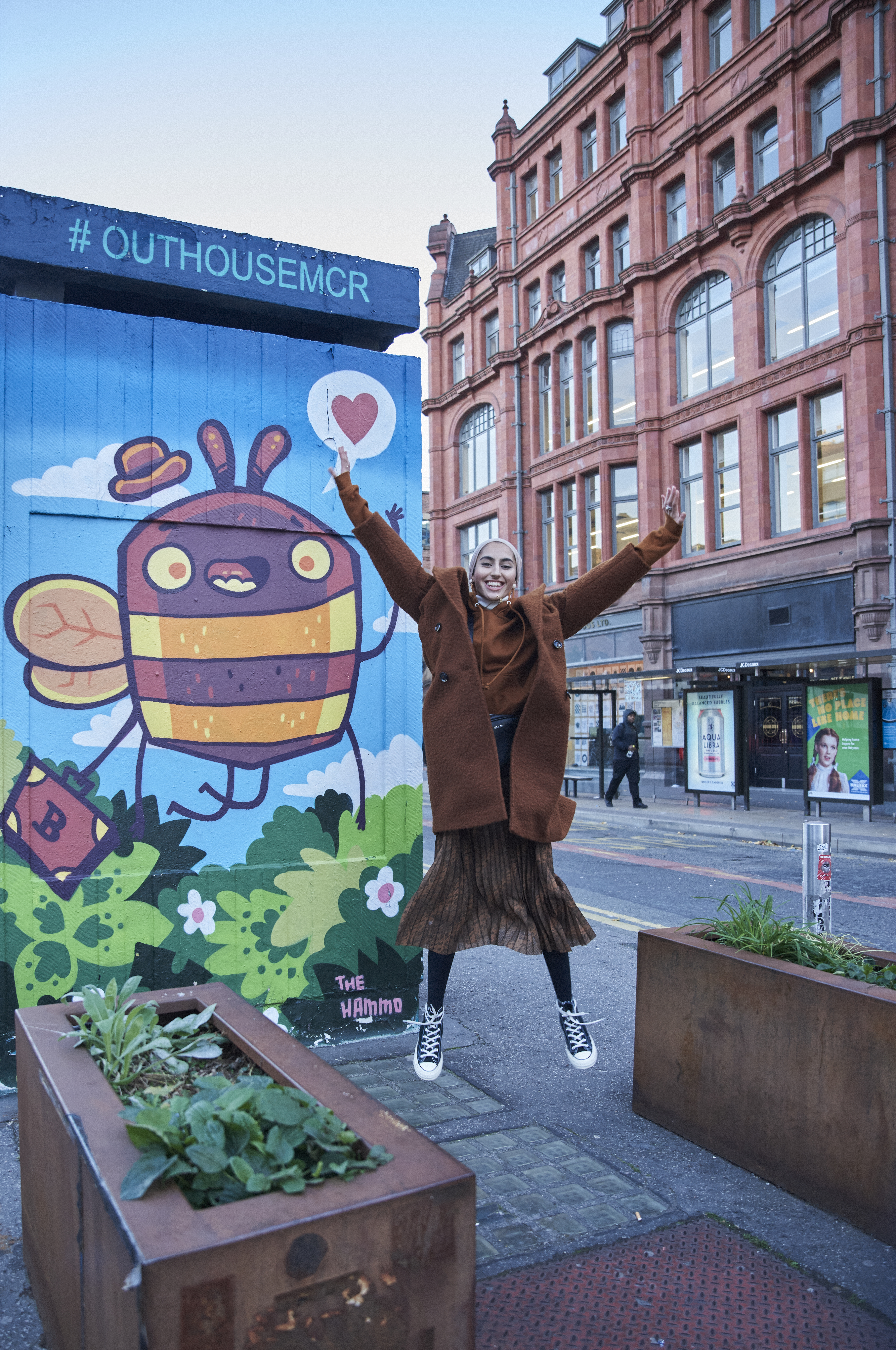 Woman jumping with joy in front of colourful murals