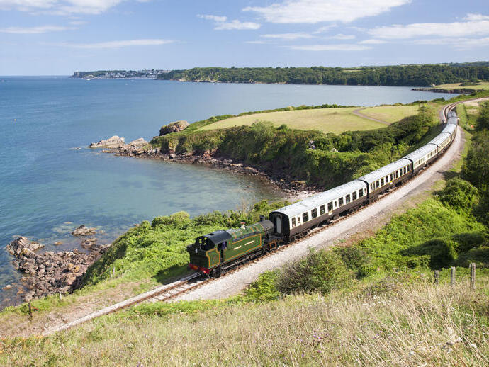 Tren de vapor en una vía férrea que sigue la costa