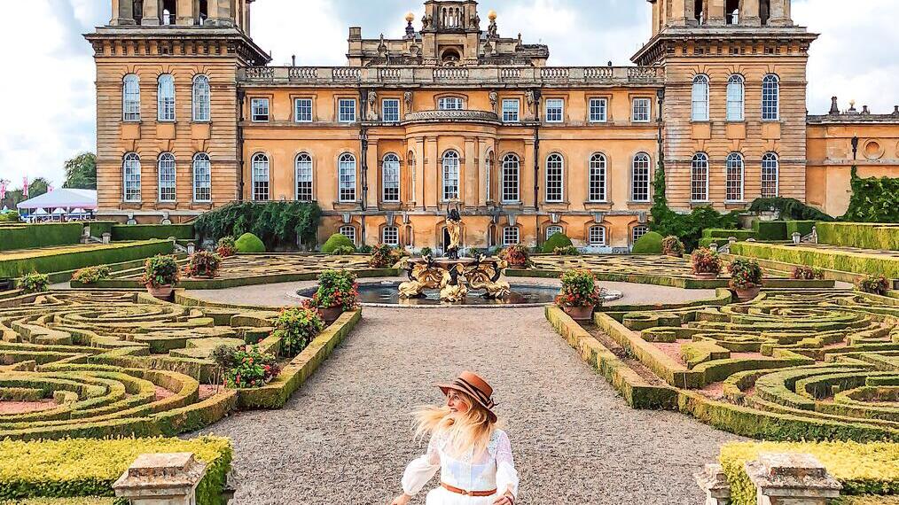 Woman walking through the formal gardens in front of a palace