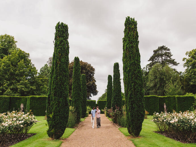Two young men walk through ornate gardens