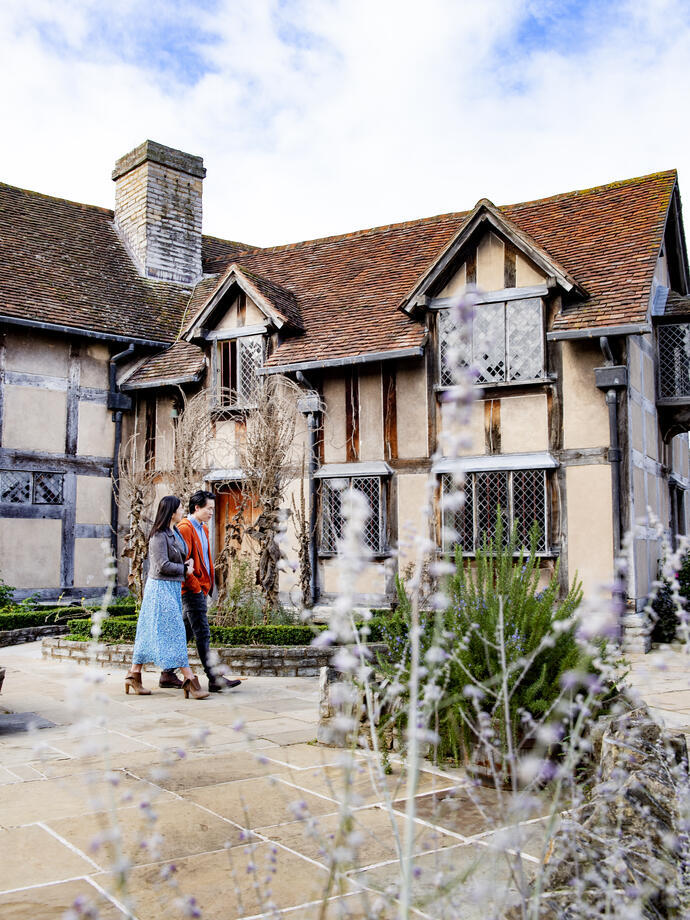 Un hombre y una mujer paseando por el exterior de una casa Tudor