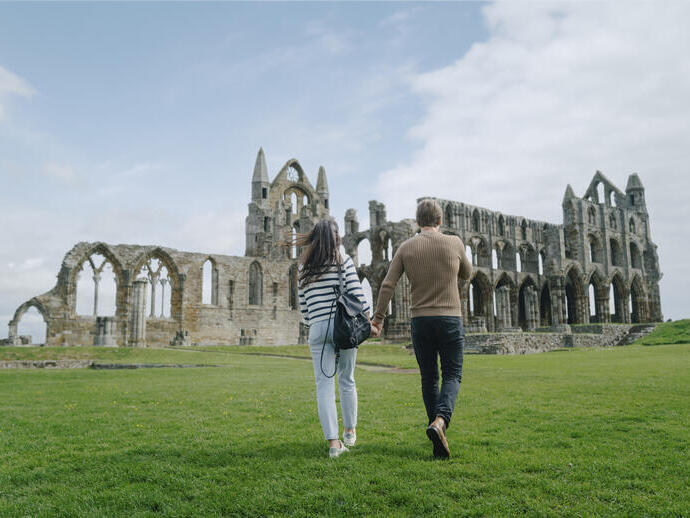 A man and woman walking towards a heritage Abbey building