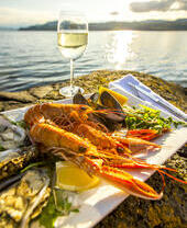 Selection of seafood on a plate with a glass of wine by the water