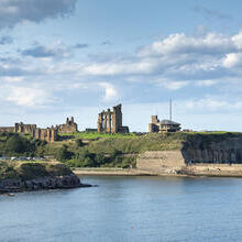 View of priory and castle ruins and a coastguard station on the coast